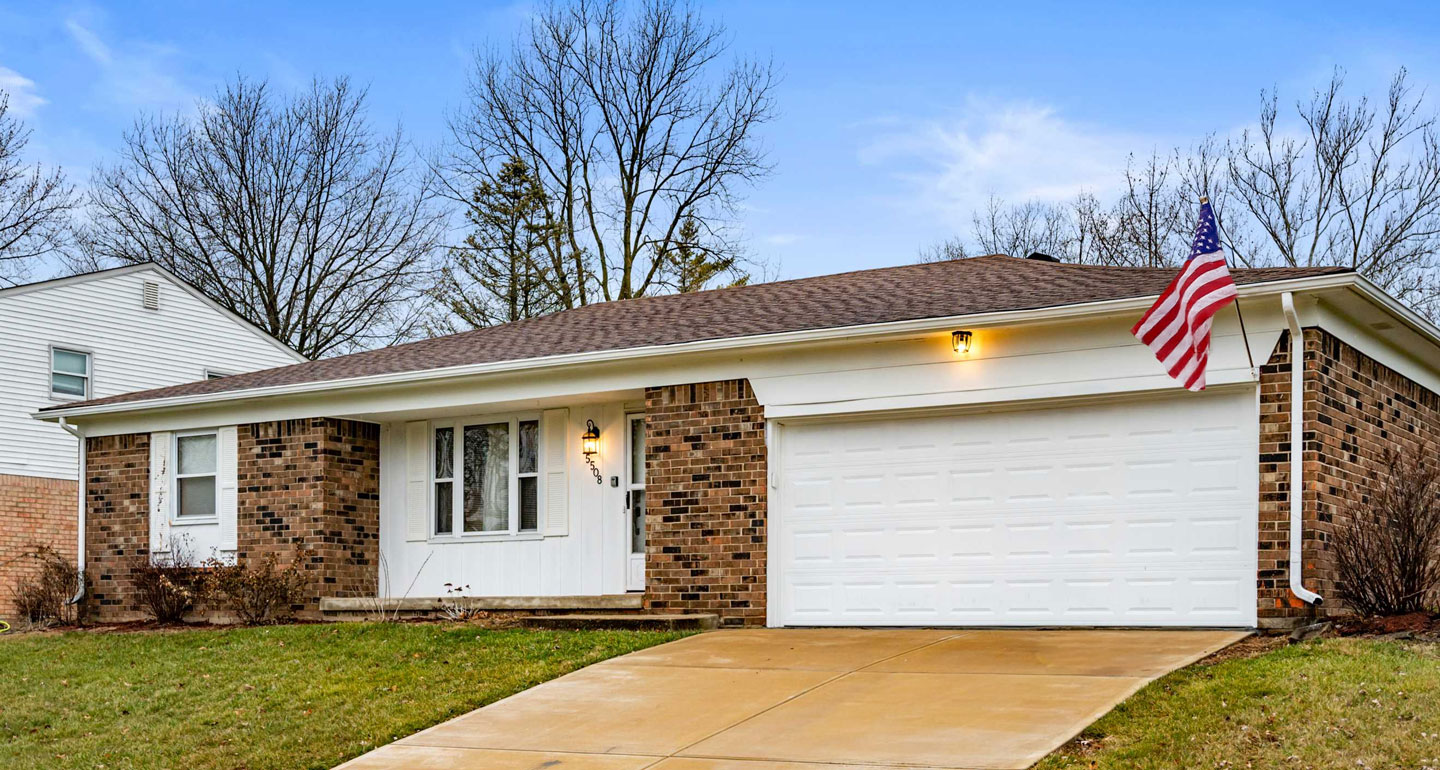Exterior of a ranch-style house flying an American flag.